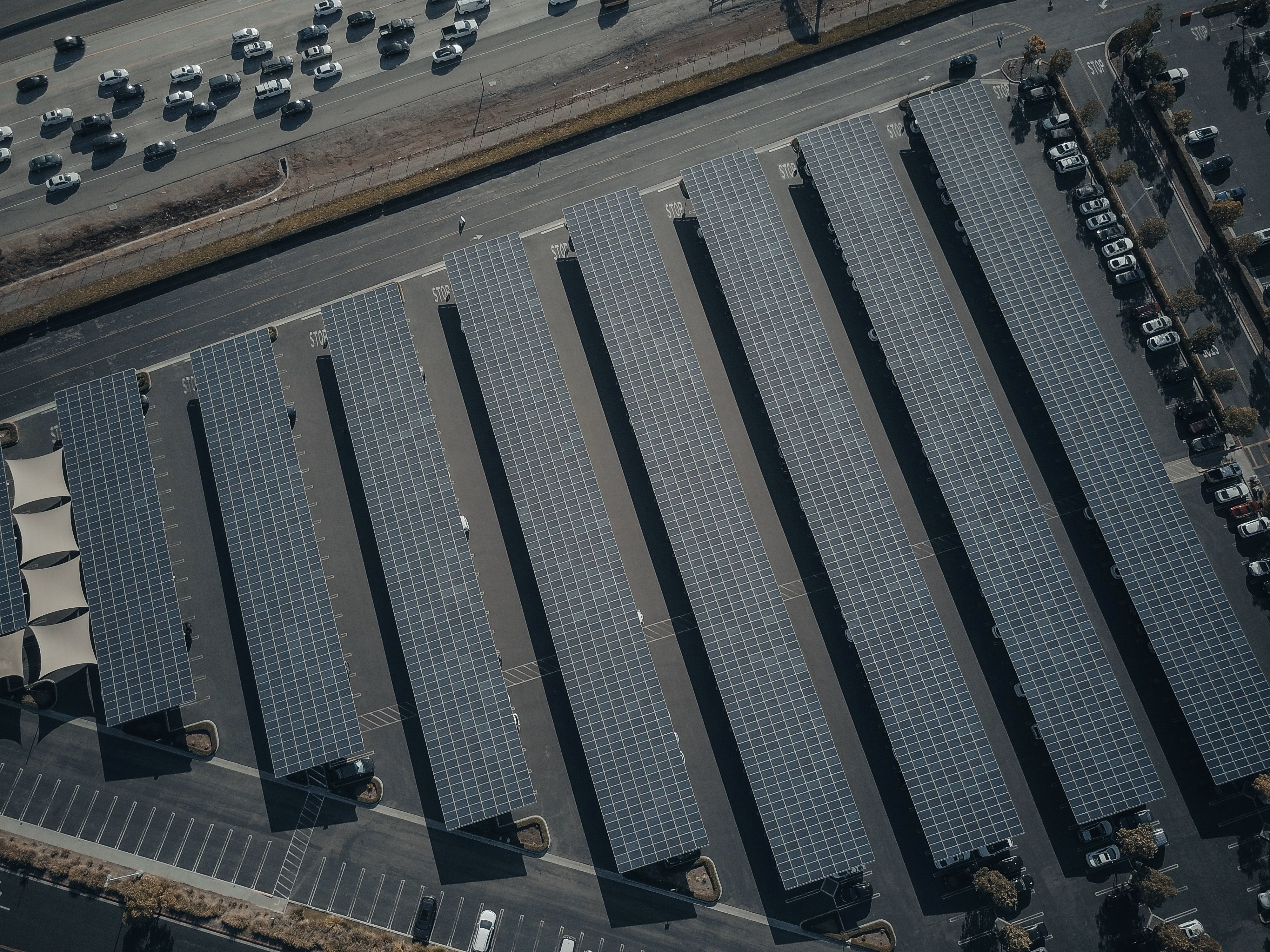 Aerial view of a solar farm next to a parking lot, illustrating clean energy reducing carbon emissions