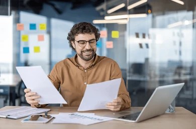 Person reviewing paperwork and documents — comparing full policy terms rather than premium alone
