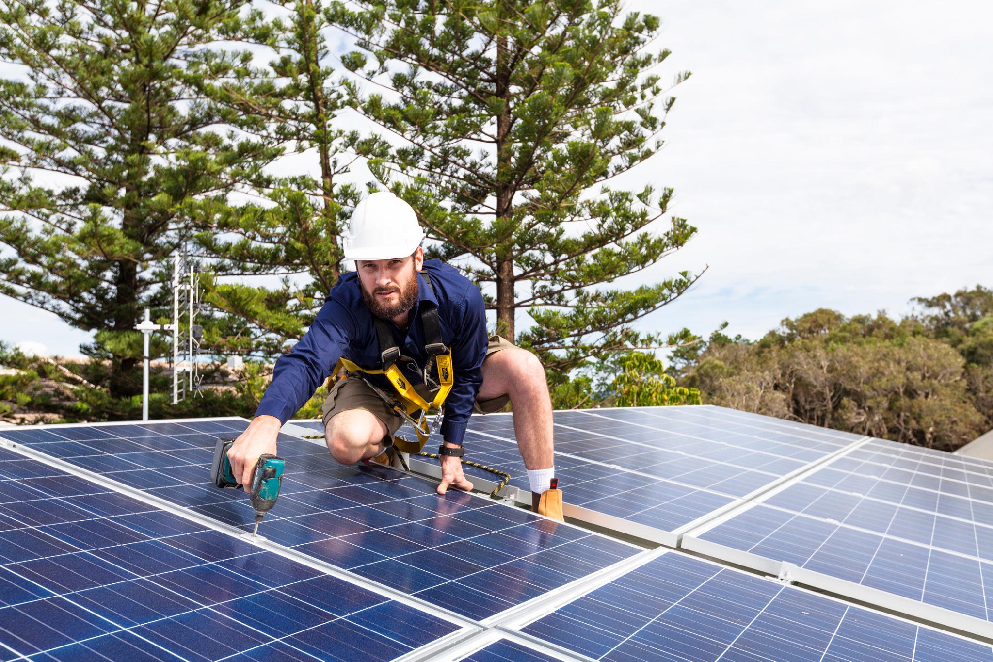 Technician installing residential solar panels to reduce electricity costs